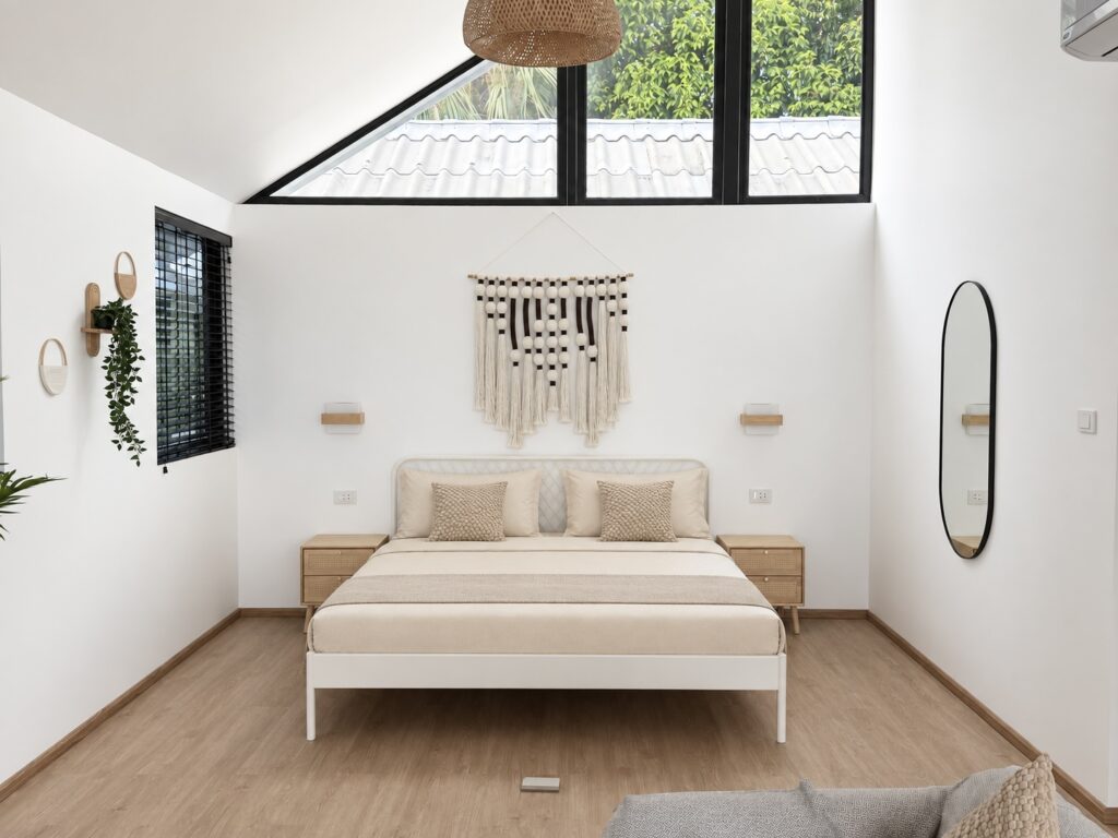 Wide bedroom view with a double bed, wall mirror and high pitched ceiling.