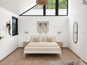 Wide bedroom view with a double bed, wall mirror and high pitched ceiling.
