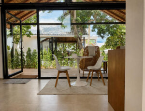 White dining table and mixed seating beside the full-height glass doors.