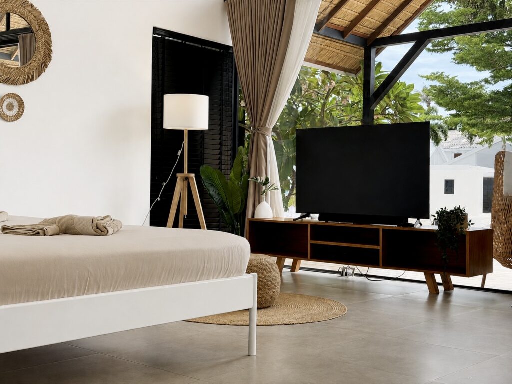 Double bed and television beside the tall glass doors and curtains.
