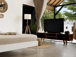 Double bed and television beside the tall glass doors and curtains.