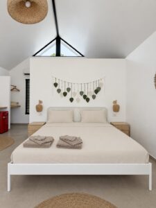 Double bed beneath leaf wall decor and a high pitched ceiling.