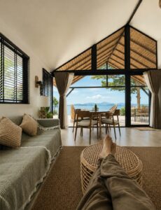 Living room with sofas and woven furniture facing the terrace and sea.