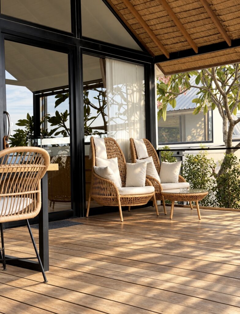 Wide view of the terrace lounge chairs, dining corner and glass doors.