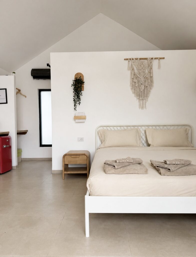 Double bed with folded towels beneath a macrame wall hanging.