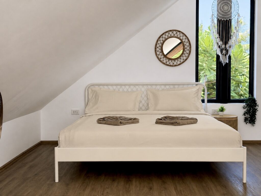 Loft bed beneath the sloping roof beside a tall triangular window.
