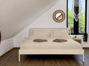 Loft bed beneath the sloping roof beside a tall triangular window.