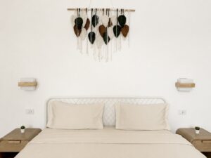 Front view of the double bed with wooden bedside tables and leaf wall decor.