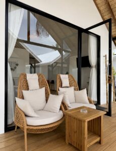 Two woven chairs with white cushions and a side table on the terrace.