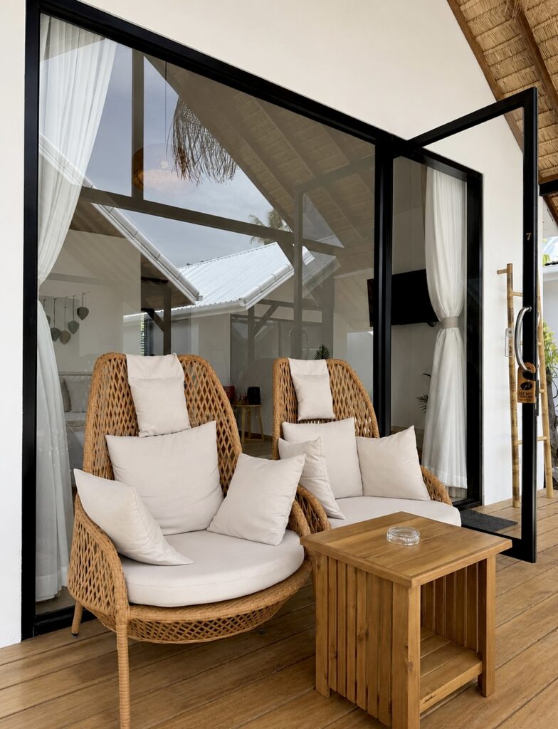 Two woven chairs with white cushions and a side table on the terrace.
