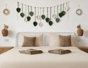 Front view of the double bed, folded towels and hanging leaf wall decor.