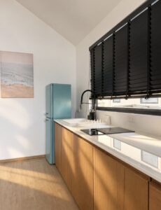 Long kitchen counter, wooden cabinets and turquoise refrigerator.