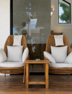 Two cushioned woven lounge chairs and a wooden table on the terrace.
