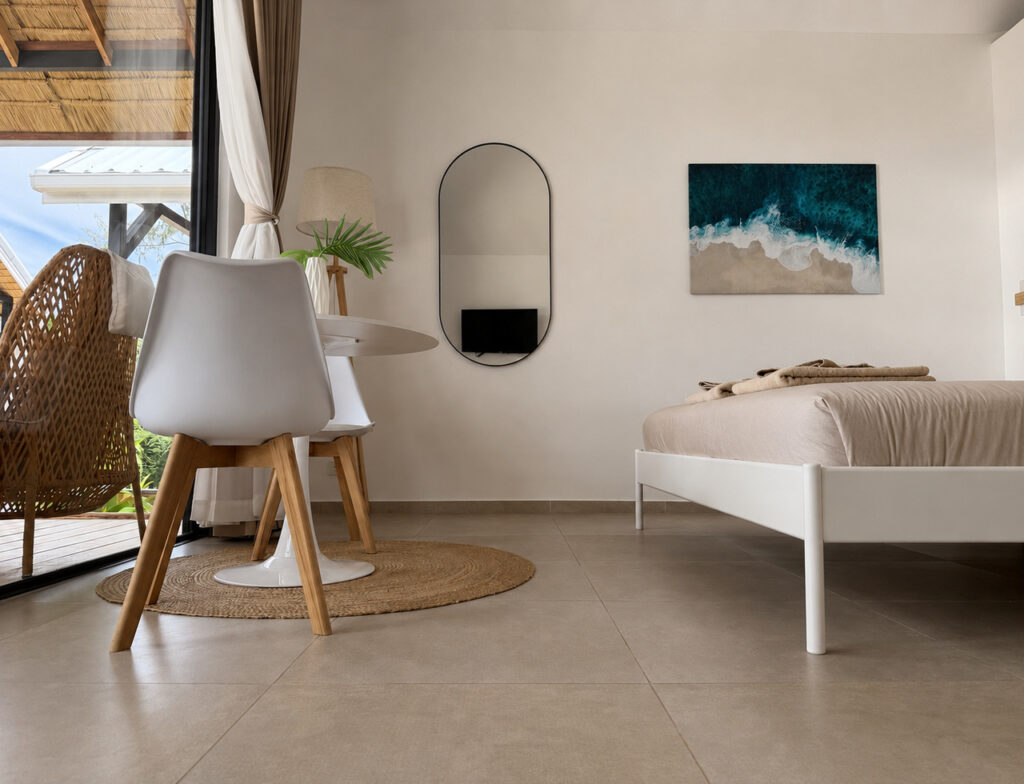 Wide bedroom view with a dining table beside the glass front and terrace seating.