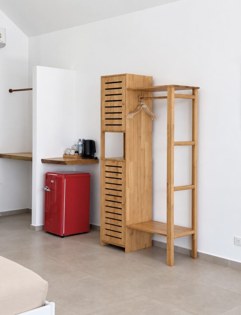 Wooden clothes rack and refreshment corner with a red mini refrigerator and kettle.