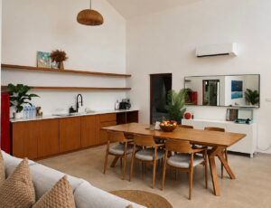 Open living area with a sofa, wooden dining table and fitted kitchen.