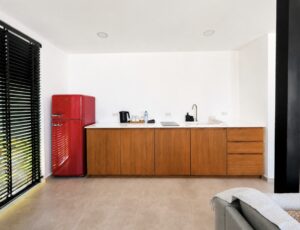 Wide view of the kitchen counter, wooden cabinets and red refrigerator.