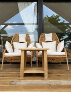 Two woven chairs and a wooden table in front of the glass doors.