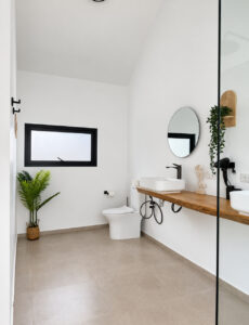 Bathroom with a long wooden vanity, countertop basins, mirrors and toilet.