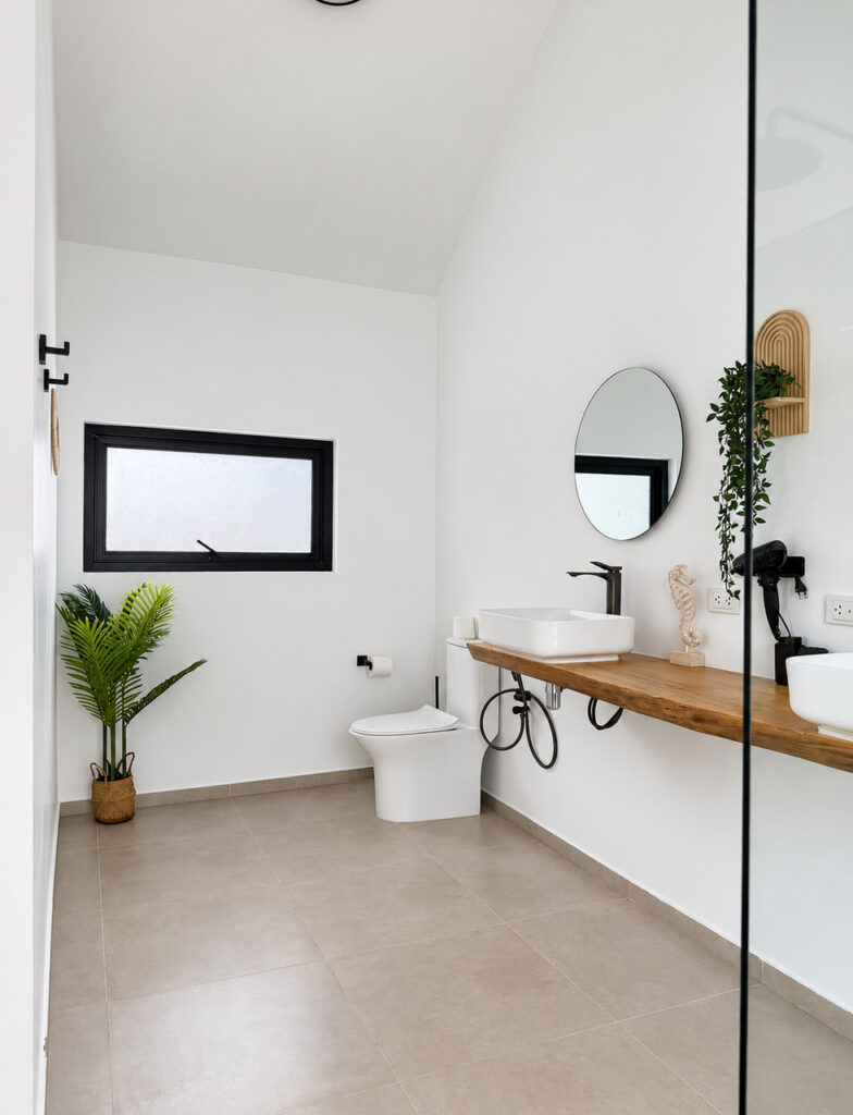 Bathroom with a long wooden vanity, countertop basins, mirrors and toilet.