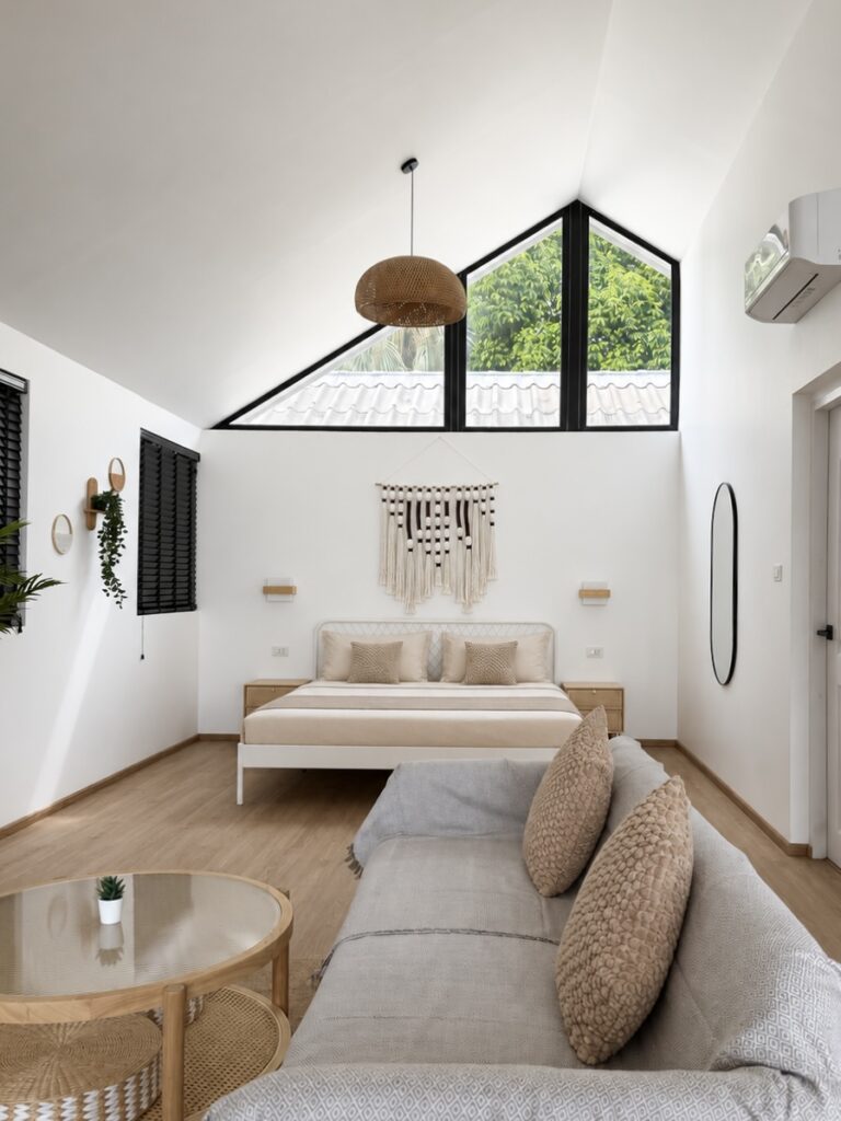 Open room with a double bed, sofa, coffee table and high triangular glazing.