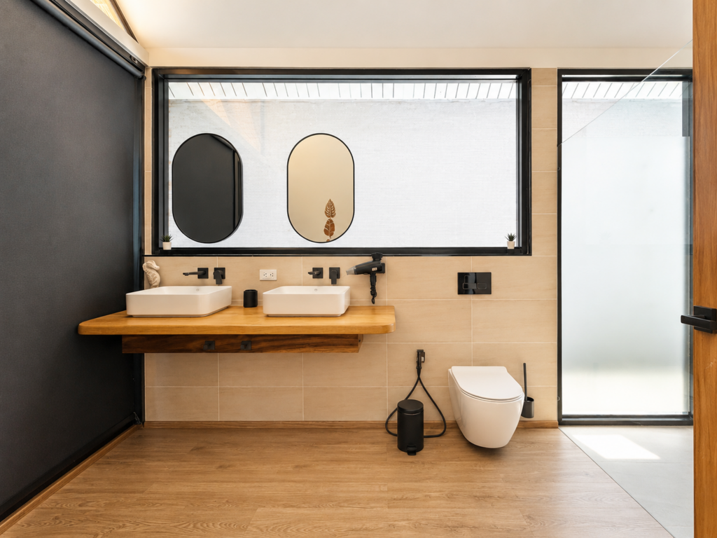 Bathroom with twin countertop basins, oval mirrors and a wall-hung toilet.