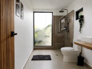 Bathroom with a shower, toilet, countertop vanity and tall frosted window.