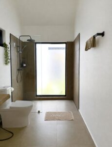 Bathroom with a shower, toilet, basin and tall frosted window.