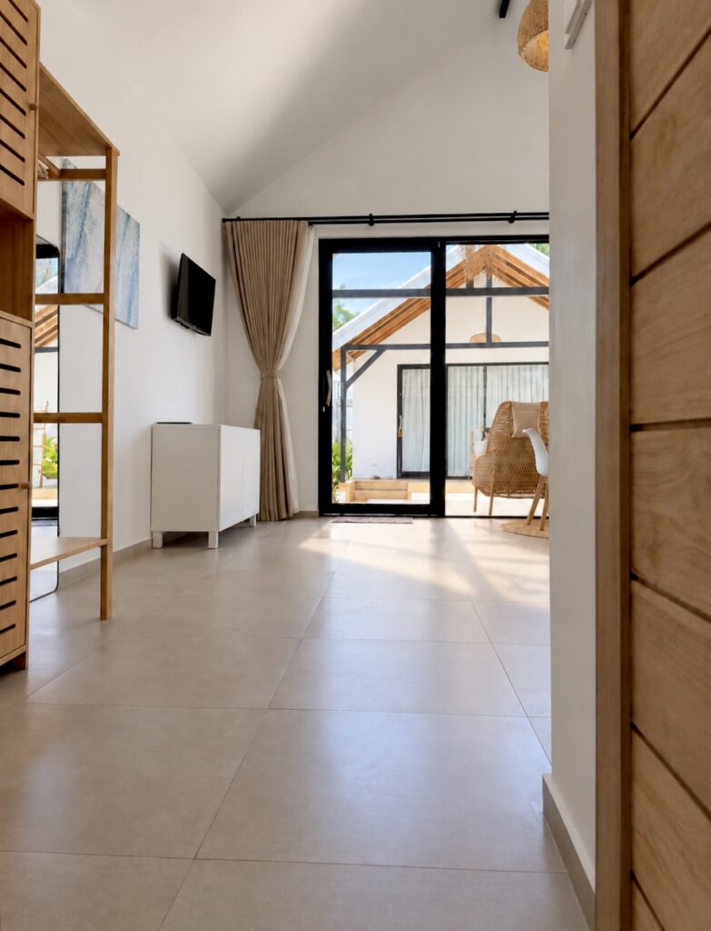 Wide view across the tiled room towards the glass entrance and terrace.