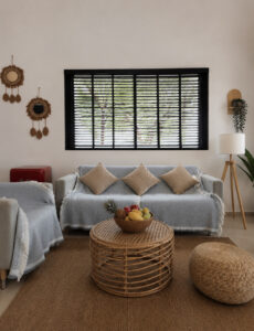 Living room with sofas, textured cushions, a woven coffee table and floor pouffe.