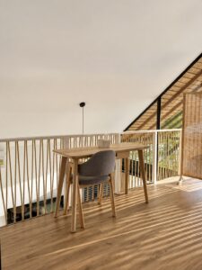 Table and chairs beside the open loft railing and tall front windows.