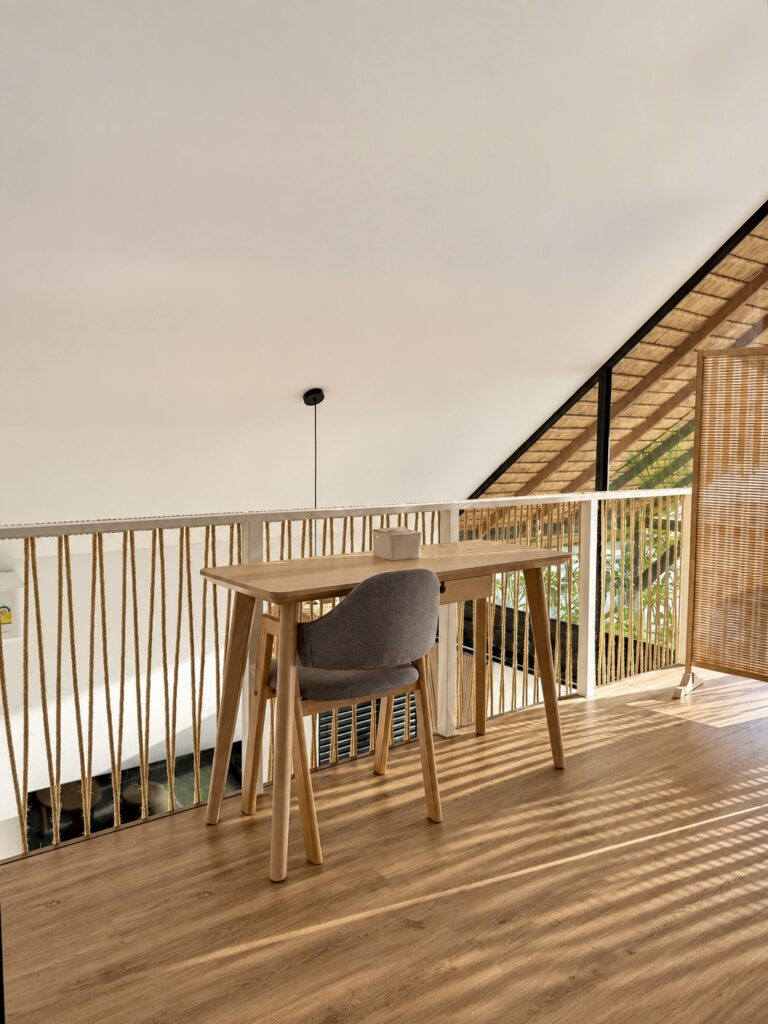 Table and chairs beside the open loft railing and tall front windows.