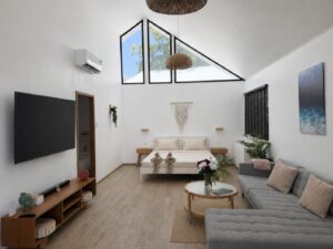 Wide view of the double bed, grey sofa, television and high triangular glazing.