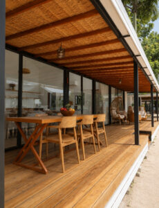 Long covered wooden terrace with dining and lounge seating beside the glass facade.