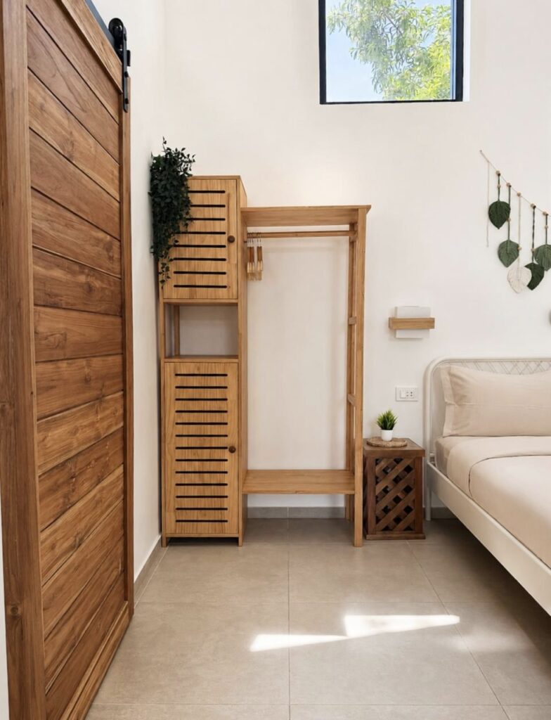 Open wooden wardrobe beside the double bed and wooden bathroom door.