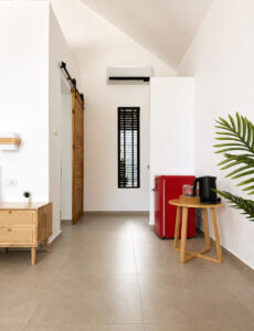 Bedroom view with a red mini refrigerator and a small refreshment stand.