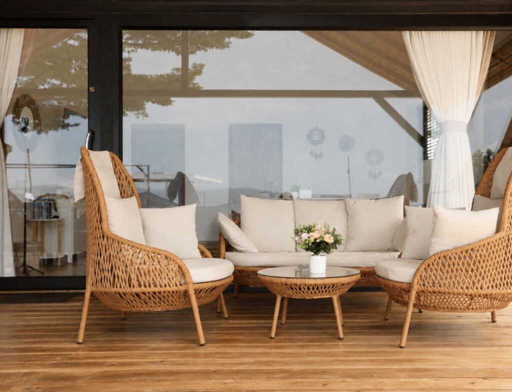 Woven outdoor sofa and lounge chairs with white cushions and a round table.