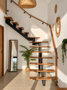 Open wooden staircase with a tall mirror and a potted plant beneath it.