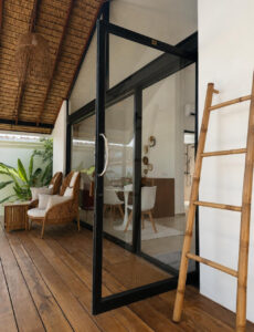 Side view of the glass facade, wooden terrace and decorative ladder.