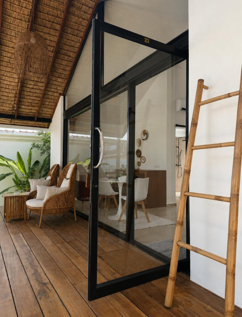 Side view of the glass facade, wooden terrace and decorative ladder.