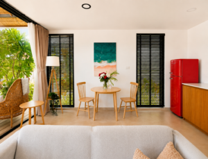 Living and dining area with a round table, wall art and red refrigerator.