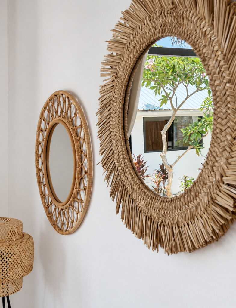 Round woven-framed mirrors reflecting greenery outside the villa.