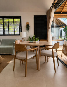 Dining table and wooden chairs beside the sofa and glass doors.