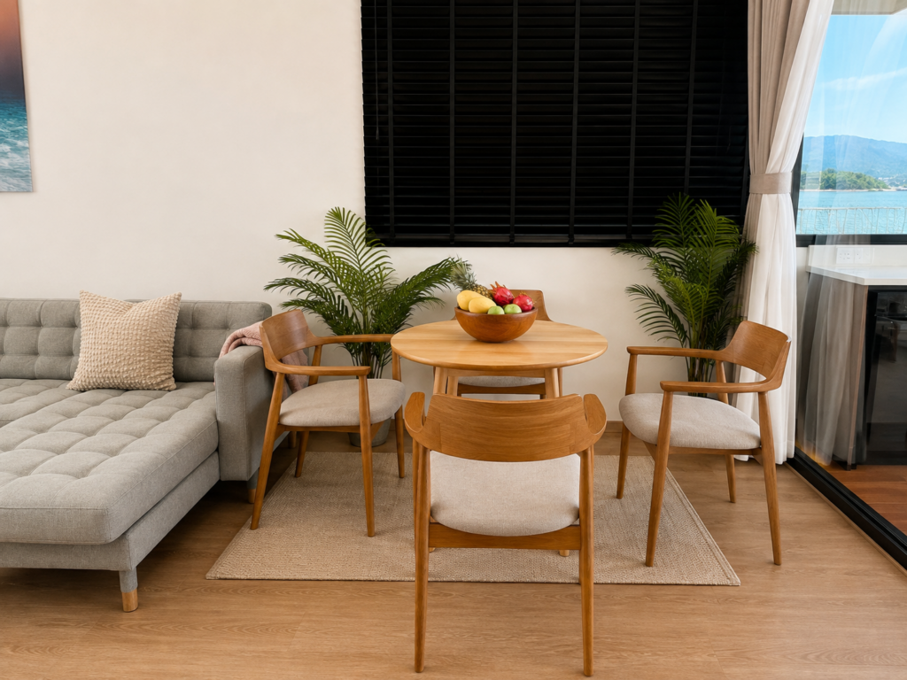 Round wooden dining table and chairs with a fruit bowl beneath a black window blind.