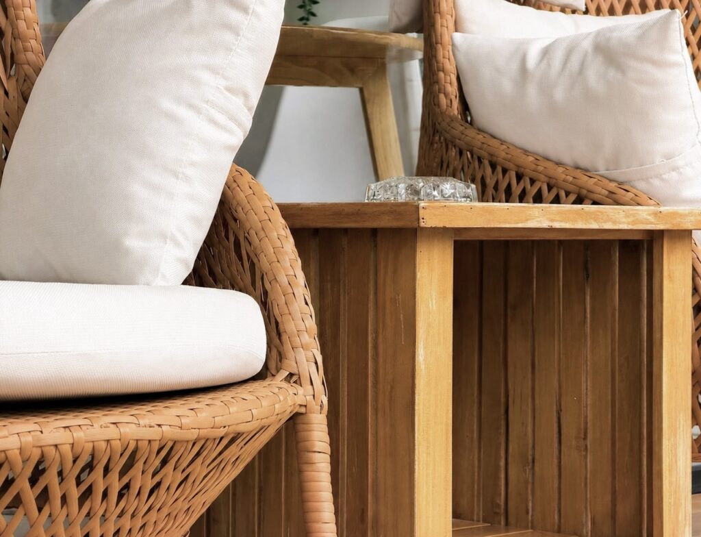 Close view of woven terrace chairs, white cushions and a wooden side table.