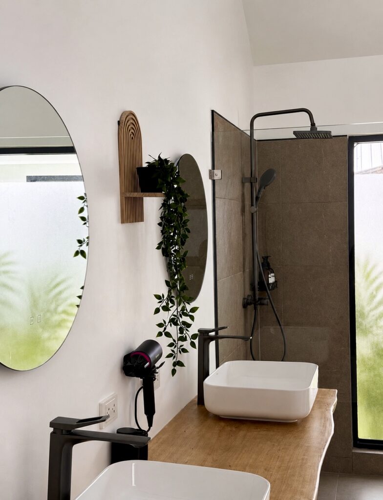 Countertop basin, wall mirror and shower area beside a frosted window.