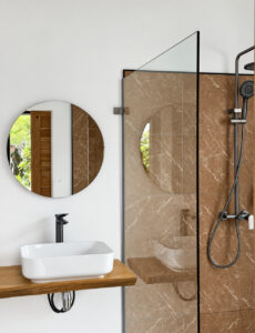Countertop basin and shower with a glass screen and overhead showerhead.