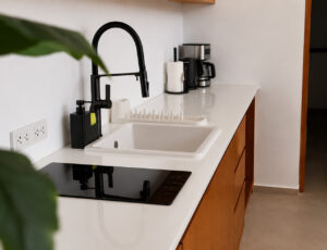Kitchen with an induction hob, white sink, black tap and coffee maker.