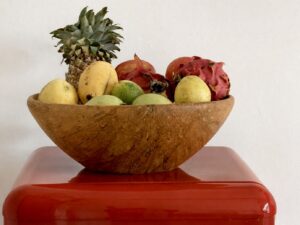 Wooden bowl of fruit on top of the red mini refrigerator.