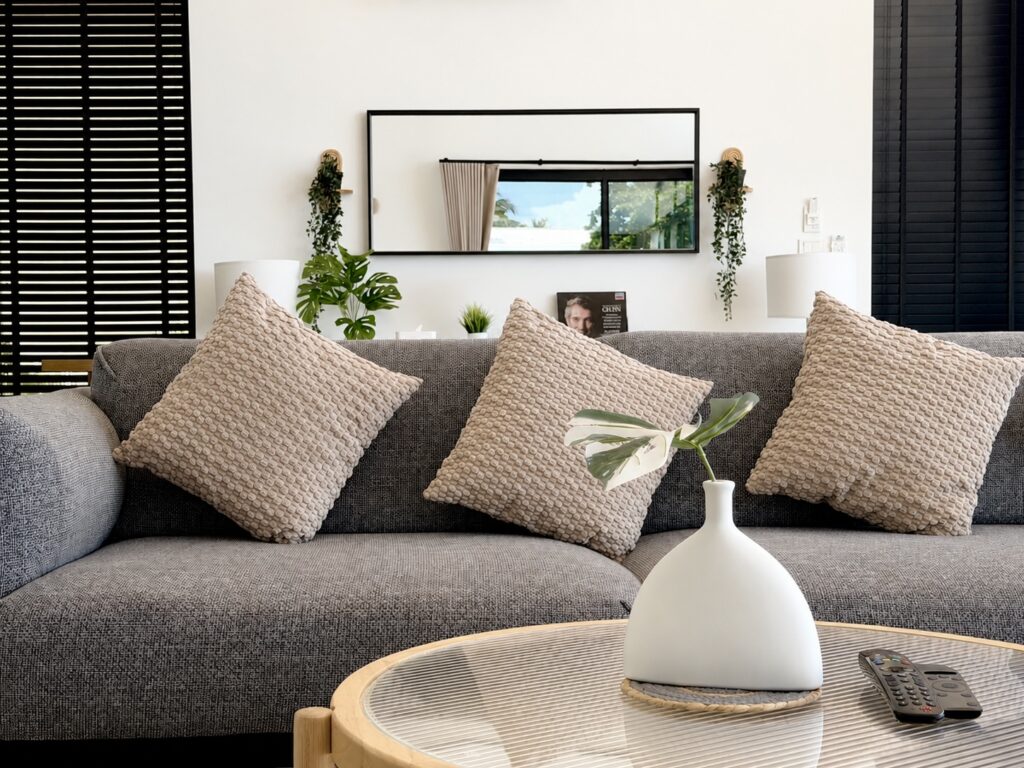 Grey sofa with textured cushions and a round coffee table with a white vase.